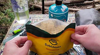 Сублімована їжа SubliMate для походу Мак енд чіз SubliMate у пакованні біля туристичного спорядження перед додаванням води