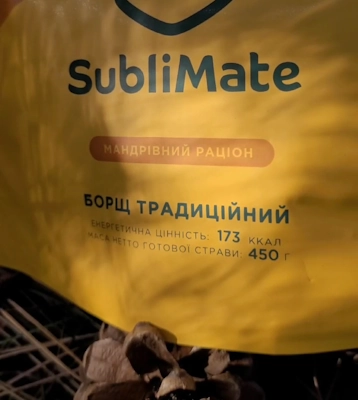 Апетитний борщ у дерев’яній мисці з традиційною ложкою, на фоні річки та вечірнього пейзажу