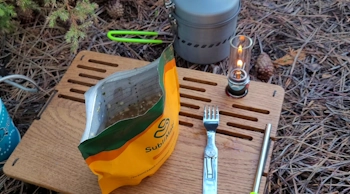 Приготований грузинський сливовий суп з яловичиною в упаковці SubliMate серед похідного спорядження — туристична їжа швидкого приготування