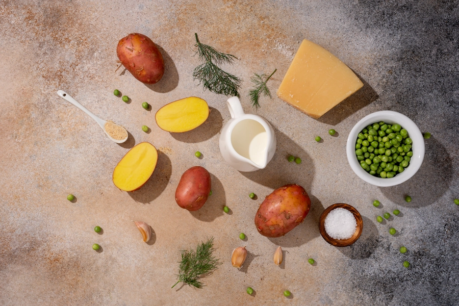 Овочі і продукти для приготування страви пюре з горошком — цілі і розрізані картоплини зелений горошок сіль сир молоко часник спеції кріп на фоні