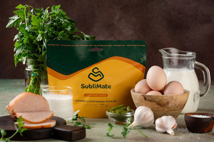 Склад мандрівного сніданку SubliMate у кадрі: натуральні яйця, молоко, зелена квасоля, часник, петрушка та копчена курка — усе для ситного старту дня.
