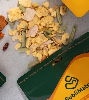 Сублімований сніданок SubliMate: курка, омлет і овочі, що висипані з пакету на стіл.