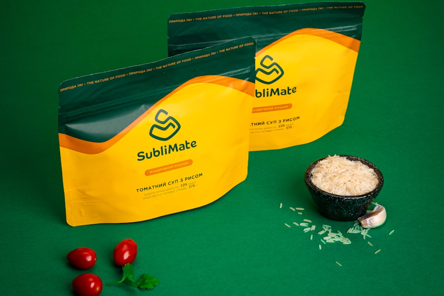Упаковки SubliMate з томатним супом з рисом на зеленому фоні — натуральна сублімована їжа без консервантів для подорожей.
