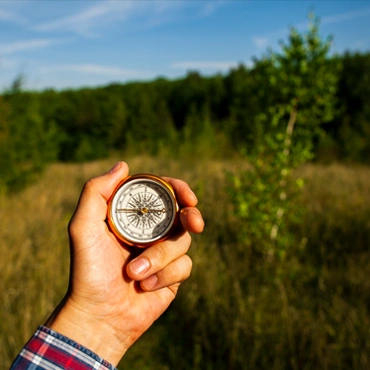Компас у Карпатах — напрямок до нових пригод Рука з компасом на тлі зеленої карпатської галявини під сонячним небом