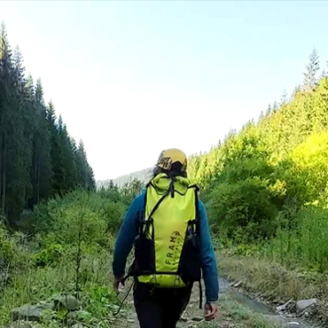 Соло-похід у горах — шлях до себе турист іде гірською стежкою вздовж річки серед лісу в сонячний день, символізуючи спокій і свободу соло-подорожі